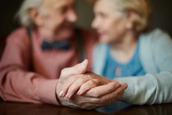 Mains d'un couple sénior se tenant tendrement
